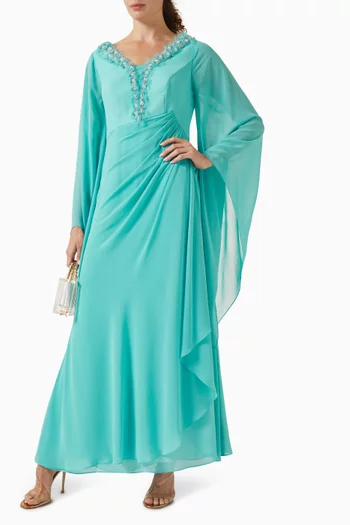 فستان طويل بفتحة رقبة على شكل حرف V مزينة بشرّابات وتطريزات بالكريستال