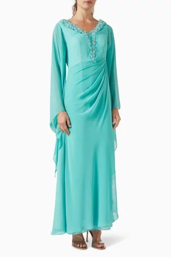 فستان طويل بفتحة رقبة على شكل حرف V مزينة بشرّابات وتطريزات بالكريستال